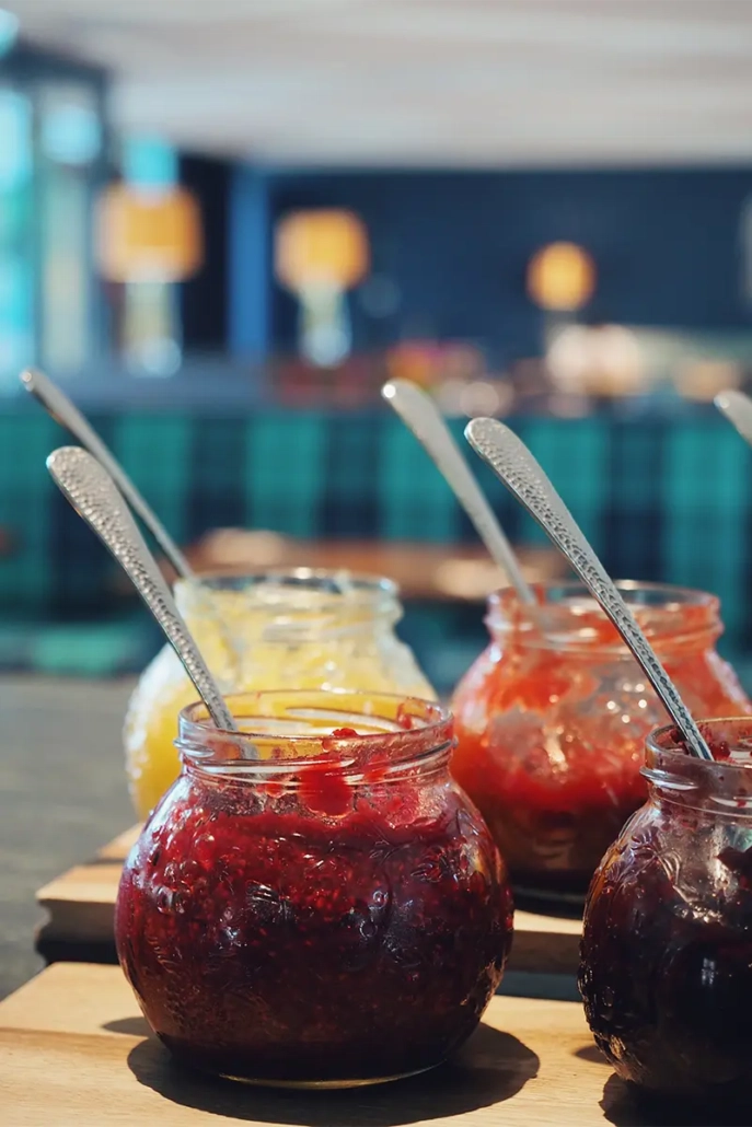 Vier Einmachgläser mit Marmelade und langen Löffeln