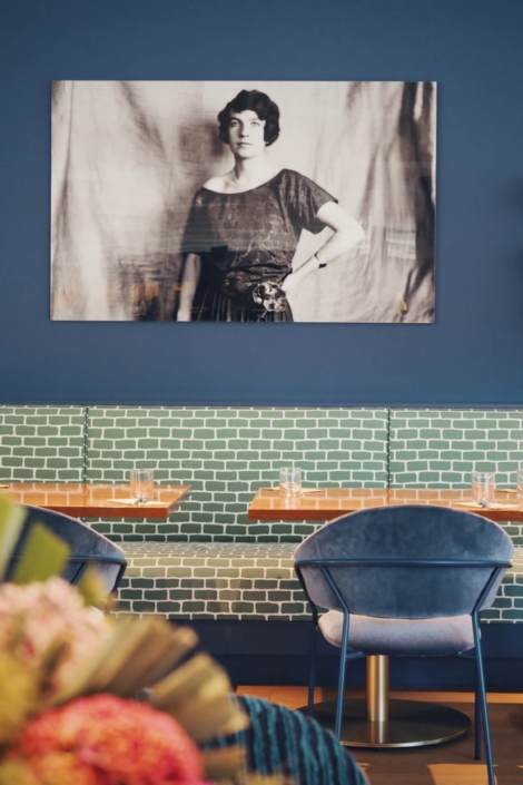 Ein stilvolles, Schwarz-Weiß-Portrait von Edith Haberland-Wagners über einer Sitzback im Speiseraum des Fräulein Wagner Restaurants.